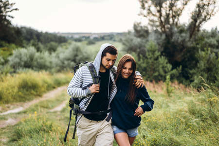 Young couple with backpacks on their backs smiling and walking in the forest, enjoy the walk.の写真素材