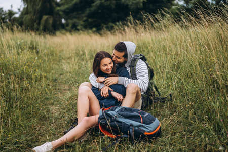Young couple with backpacks on their backs smiling and walking in the forest, enjoy the walk.の写真素材