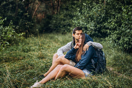 Young couple with backpacks on their backs smiling and walking in the forest, enjoy the walk.の写真素材