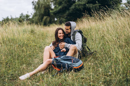 Young couple with backpacks on their backs smiling and walking in the forest, enjoy the walk.の写真素材
