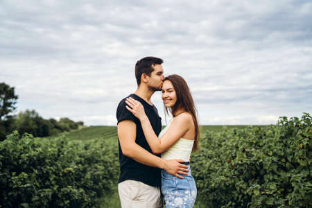 Young loving couple gently hugging on the background of green currant plantations. Love Story.の写真素材