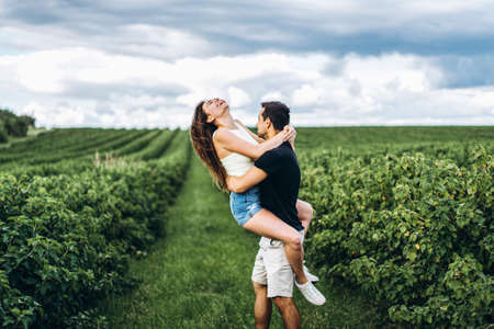 A tender loving couple walking in a field of currant. Man whirls woman in her arms. Love story.の写真素材