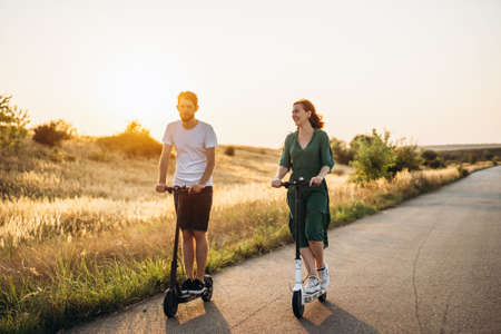 Young couple on vacation having fun driving electric scooter on the road in the countryside. Content technologies. Copy space.の写真素材