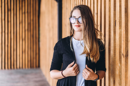 Portrait of a young woman on the wooden background with vertical boards. Beautiful girl with long...