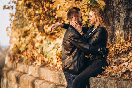 Sunny portrait of a young loving couple walking in the autumn park. They hug and smile, enjoy a walk.の写真素材