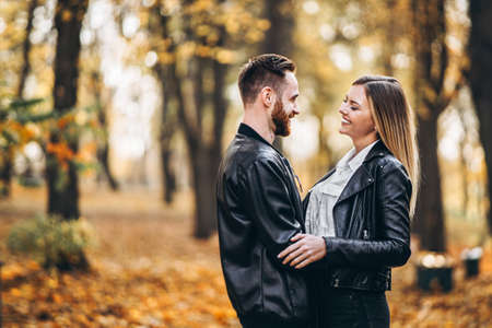 Beautiful young couple walking in the autumn park on a sunny day. They hug and smile, enjoy a walk.の写真素材