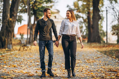 Portrait of a young loving couple. Man and woman hugging and smiling in the background of autumn park.の写真素材