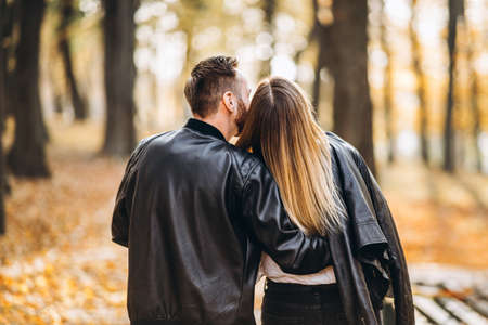 Portrait of a happy couple in love walking outdoor in the autumn park. Man and woman holding hands. Back view.の写真素材