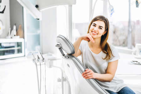 Pretty happy and smiling dental patient sitting in the dental chair at the dental officeの写真素材