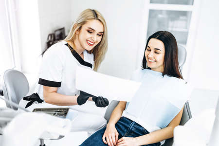 Dentist showing x-ray for the patient and explaining plan of treatmentの写真素材