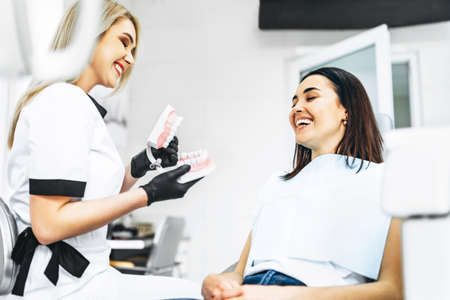 Pretty female dentist explaining way of treatment on the denture for the patient in the clinicの写真素材