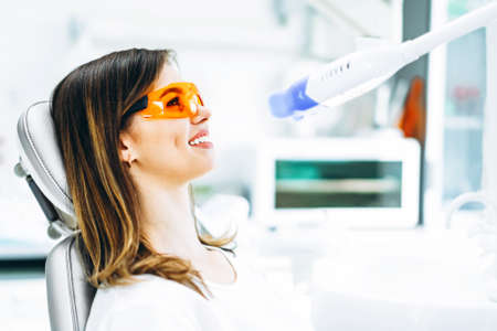 Teeth whitening procedure for pretty happy female patient in a dental clinicの写真素材