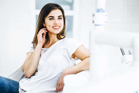Pretty happy and smiling dental patient sitting in the dental chair at the dental officeの写真素材