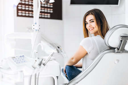 Pretty happy and smiling dental patient sitting in the dental chair at the dental officeの写真素材
