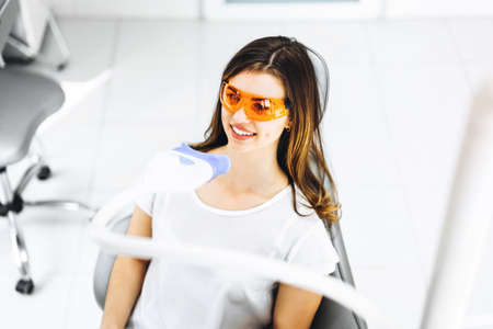 Teeth whitening procedure for pretty happy female patient in a dental clinicの写真素材