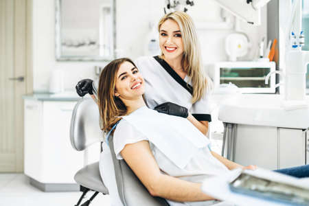 Pretty young female dentist making examination and treatment for young female patient in dental clinicの写真素材