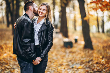 Portrait of a young loving couple. Man and woman hugging and smiling in the background of autumn park.の写真素材