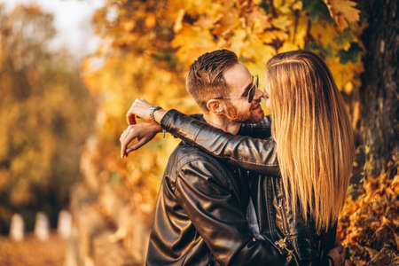 Young couple kissing on the background of the autumn park. A man raised his woman in his arms.の写真素材