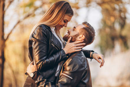 Young couple kissing on the background of the autumn park. A man raised his woman in his arms.の写真素材