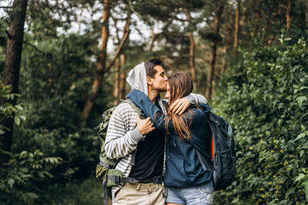 Young couple with backpacks on their backs smiling and walking in the forest, enjoy the walk.の写真素材