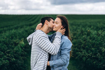 Young loving couple gently hugging on the background of green currant plantations. Love Story.の写真素材