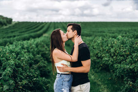 Young loving couple gently hugging on the background of green currant plantations. Love Story.の写真素材