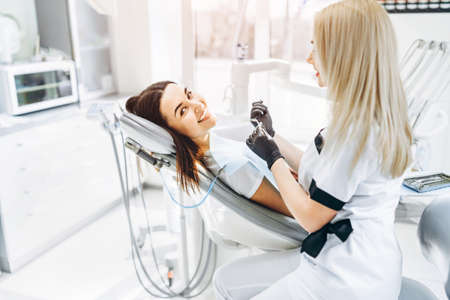 Pretty young female dentist making examination and treatment for young female patient in dental clinicの写真素材