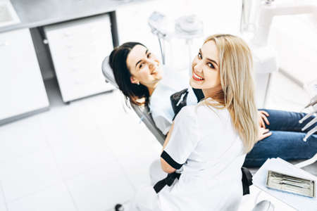 Pretty young female dentist making examination and treatment for young female patient in dental clinicの写真素材