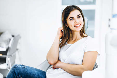 Pretty happy and smiling dental patient sitting in the dental chair at the dental officeの写真素材