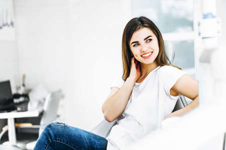 Pretty happy and smiling dental patient sitting in the dental chair at the dental officeの写真素材