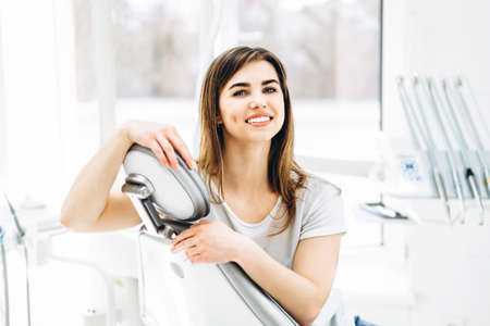 Pretty happy and smiling dental patient sitting in the dental chair at the dental officeの写真素材