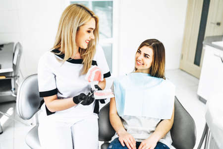 Pretty female dentist explaining way of treatment on the denture for the patient in the clinicの写真素材