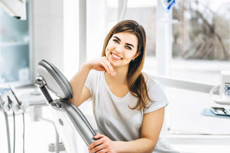 Pretty happy and smiling dental patient sitting in the dental chair at the dental officeの写真素材