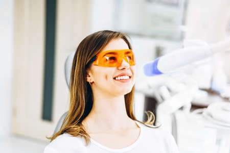 Teeth whitening procedure for pretty happy female patient in a dental clinicの写真素材