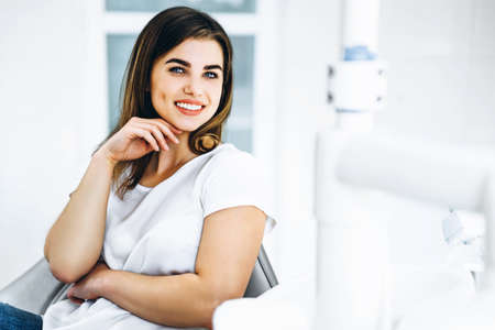 Pretty happy and smiling dental patient sitting in the dental chair at the dental officeの写真素材