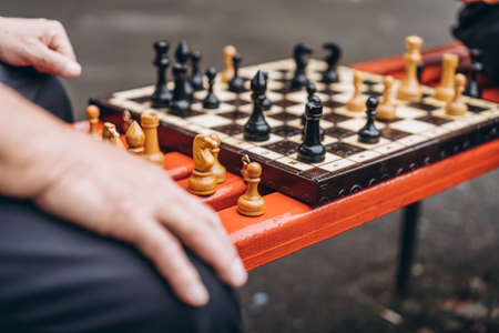 Two senior adult men playing chess on the bench outdoors in the parkの写真素材