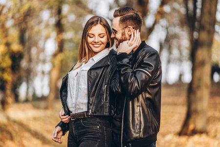 A young couple in love walking in the autumn park on a sunny day. The man gently hugs the woman....