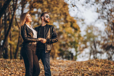 Beautiful young couple walking in the autumn park on a sunny day. They hug and smile, enjoy a walk.の写真素材