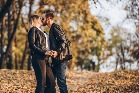 Beautiful young couple walking in the autumn park on a sunny day. They hug and smile, enjoy a walk.の写真素材