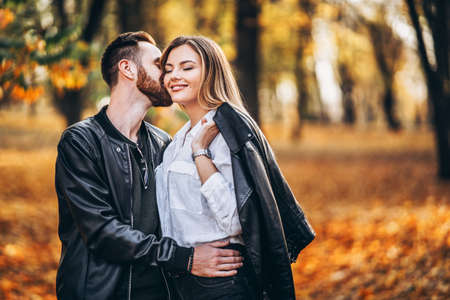 Portrait of a young loving couple. Man and woman hugging and smiling in the background of autumn park.の写真素材