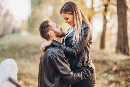Young couple kissing on the background of the autumn park. A man raised his woman in his arms.の写真素材