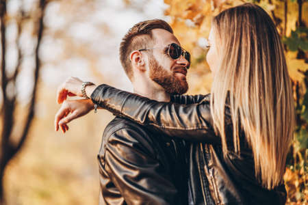 Sunny portrait of a young loving couple walking in the autumn park. They hug and smile, enjoy a walk.の写真素材