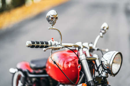 Red custom old fashioned motorcycle on the road in the forest with colorful blurred backgroundの写真素材