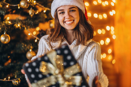 Christmas, New Year. Pretty woman in warm sweater, socks and christmas hat, decorating new year tree...