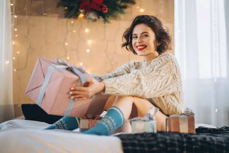 Happy and pretty brunette on the bed with gift boxes around her. New Year, Christmas, birthday, Valentineâs Day conceptの写真素材