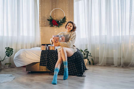 Happy and pretty brunette on the bed with gift boxes around her. New Year, Christmas, birthday, Valentineâs Day conceptの写真素材