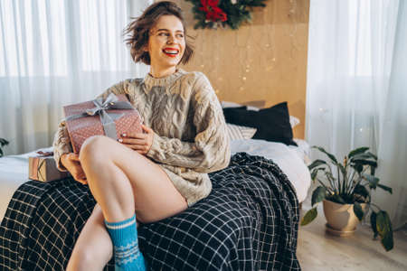Happy and pretty brunette on the bed with gift boxes around her. New Year, Christmas, birthday, Valentineâs Day conceptの写真素材