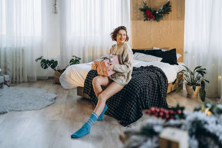 Happy and pretty brunette on the bed with gift boxes around her. New Year, Christmas, birthday, Valentineâs Day conceptの写真素材