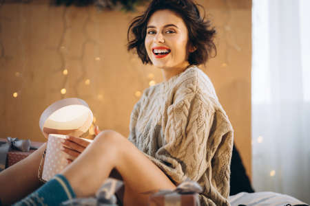 Happy and pretty brunette on the bed with gift boxes around her. New Year, Christmas, birthday, Valentineâs Day conceptの写真素材
