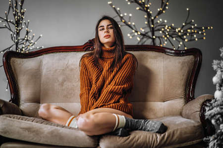 Pretty brunette girl in sweater and lingerie relaxing on the couch indoorsの写真素材